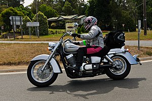 Silver cruiser motorcycle ridden on suburban road