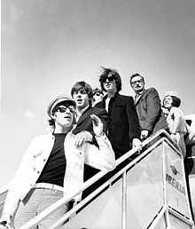 Photo en noir et blanc d'un groupe d'hommes et une femme, descendant d'un avion.