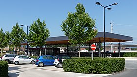 Die Westseite: unter dem Dach links die Bäckerei, rechts der Fahrradständer und im Vordergrund der Parkplatz