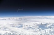 View of the crescent moon through the top of the earth's atmosphere. Photographed above 21.5°N, 113.3°E. by the International Space Station crew Expedition 13 over the South China Sea, just south of Macau.