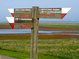 Wegwijzer Zevenwoudenpad en Friese Kustpad bij de Waddenzeedijk