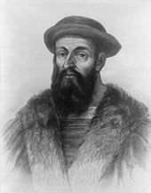 Head and shoulders of a heavily-bearded man wearing a cloak and a soft hat