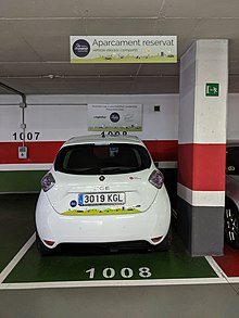 Coche eléctrico aparcado en una plaza de garaje. Se ve la matrícula y la parte trasera del coche.