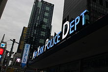 A glowing blue NYPD Times Square sign with the initial letters in white