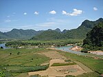 Landscape with river and densely forested hills.