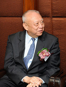 Portrait of Tung Chee-hwa wearing a black suit and a blue tie