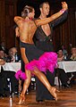 Image 15Latin dancers in their costumes. The woman is wearing backless dress with deep slits on its lower portion, while the man is wearing a shirt with top buttons open. (from Fashion)