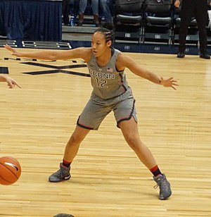 Young woman with limbs outstretched wearing Connecticut uniform