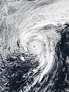 A well-developed hurricane with a defined, clear eye and prominent clouds surrounding it. A large band of clouds also extends north of the main center