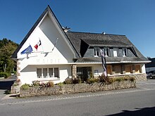 Bâtiment composé de deux parties perpendiculaires, aux murs blancs et au toit d'ardoise bleue. Ses angles, les entourages de fenêtres et le muret devant le bâtiment sont en granit brun.