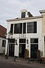 Huis met lijstgevel, gepleisterd, gewitte zijgevel. Achterhuis