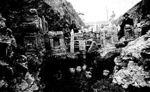 Photographie ancienne représentant des fouilles avec des stèles dégagées et des personnages posant pour la photographie.