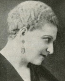 A white woman with short blond curly hair, in profile