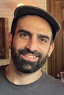 A male person wearing a hat smiling at the camera.