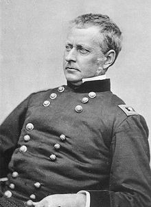 Historic photograph of the head and torso of a man in American Civil War uniform. He appears to be seated and is looking off to the right. He is clean shaven, with short gray hair. His expression is stern.