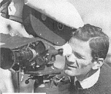 Pasolini guarda attraverso l'obiettivo di una cinepresa.