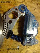 Saw braking cartridge after activation. Notice the aluminum frame has been crushed as a result of impact by moving saw blade, and the spring stretched.