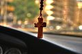 A cross necklace hanging from the rear-view mirror of a car