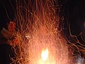 A campfire that seems to produce sparks, due to a long exposure when photographed.