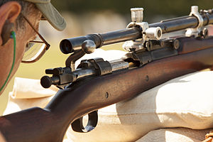 Um cartucho pode ser parcialmente visto na câmara de um rifle