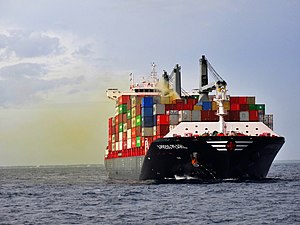 Cargo ship at sea with yellowish fumes coming from a container