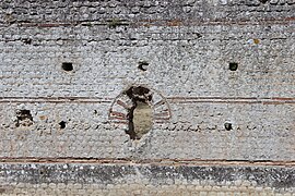 Vue d'un mur montrant une alternance rangées de moellons posés droits et en oblique et de lits de tuiles.