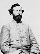 Black and white photo of a bearded man in a gray uniform with two rows of buttons.