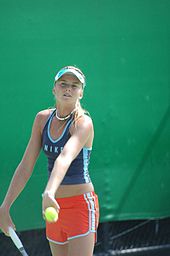 Daniela Hantuchová wearing a black top and red shorts, just about the serve the ball