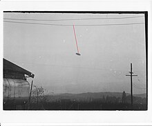 Photo en noir et blanc d'un objet en forme de disque relié à un câble par un fil hypothétique rouge.