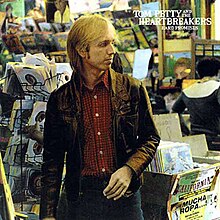 A photo of Petty standing in a record store and staring off to the side.