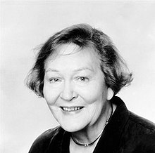 a black and white photograph of a white woman with short hair, smiling at the camera