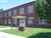 Color photo of a reb brick building, two stories tall, with a short green lawn