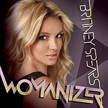 Upper bust of Britney Spears. She looks into the camera over her right shoulder. Her mouth is slightly open. She is wearing a black top with small holes. The background is composed by geometric figures in different shades of purple. In an upside down vertical direction, the words "BRITNEY SPEARS" are written in light yellow capital letters. On the lower part of the image, the word "WOMANIZER" is written in capitals with shades of light violet and light yellow.