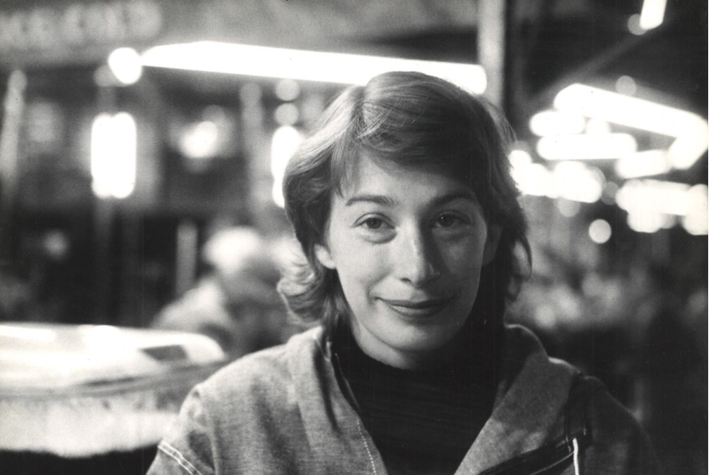 Head and shoulders portrait of woman smiling, background with lights, blurred.