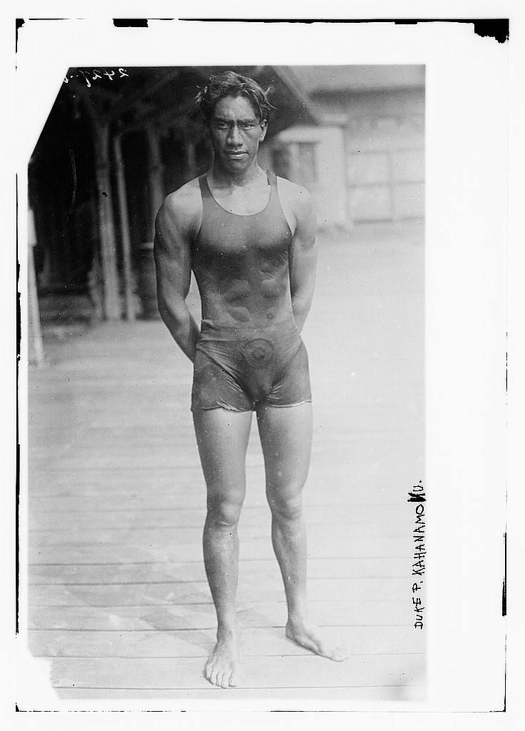 Monochrome image of muscular man facing camera, in swimsuit