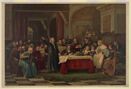 Men and women seated and standing around a table, with one man standing and pointing at something unseen at left, frescoes and heavy curtains in background