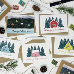 several christmas cards are laid out on a table with pine cones and other holiday decorations