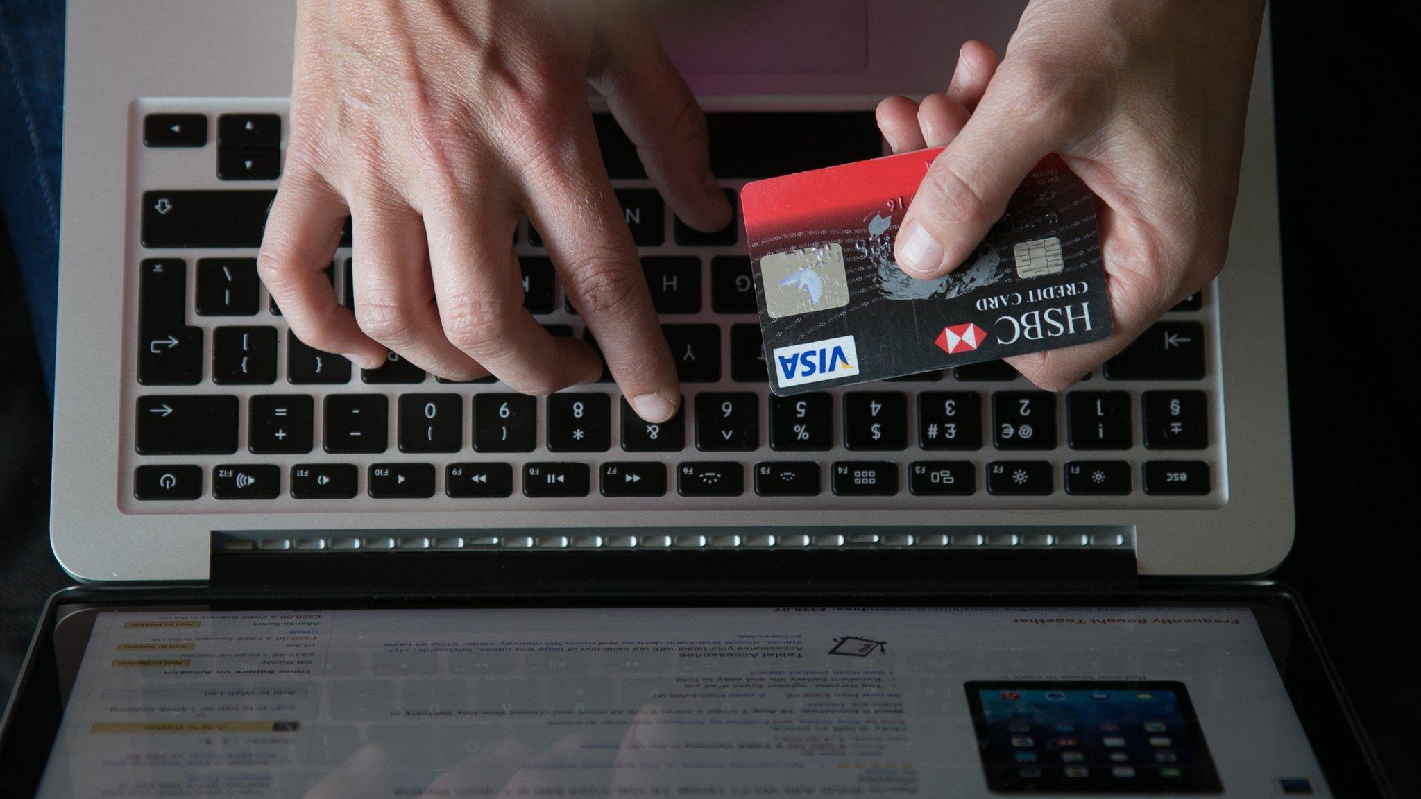 In this photo illustration a woman uses a credit card to buy something online