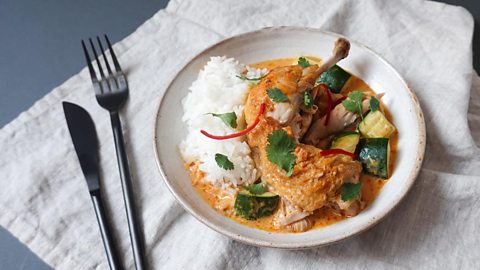 A dish filled with red Thai curry and a mound of rice