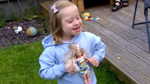 Millie from Hull holding a new barbie Mattel have created with Down’s Syndrome.