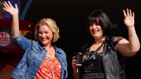 Joanna Page and Ruth Jones smile and wave to crowds of fans while filming in Barry Island