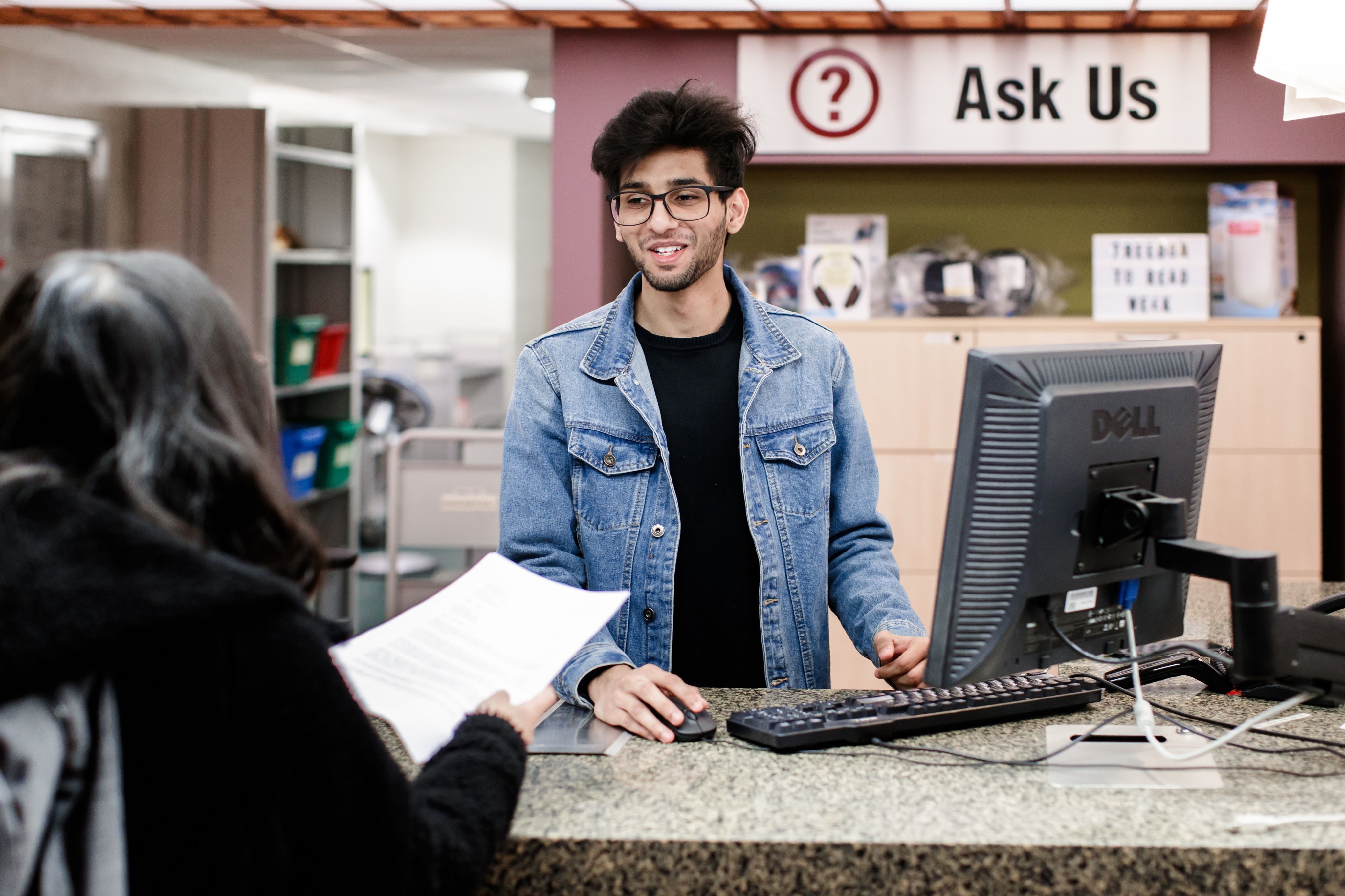 Student assistant helping a user at the Mills Library Service Desk