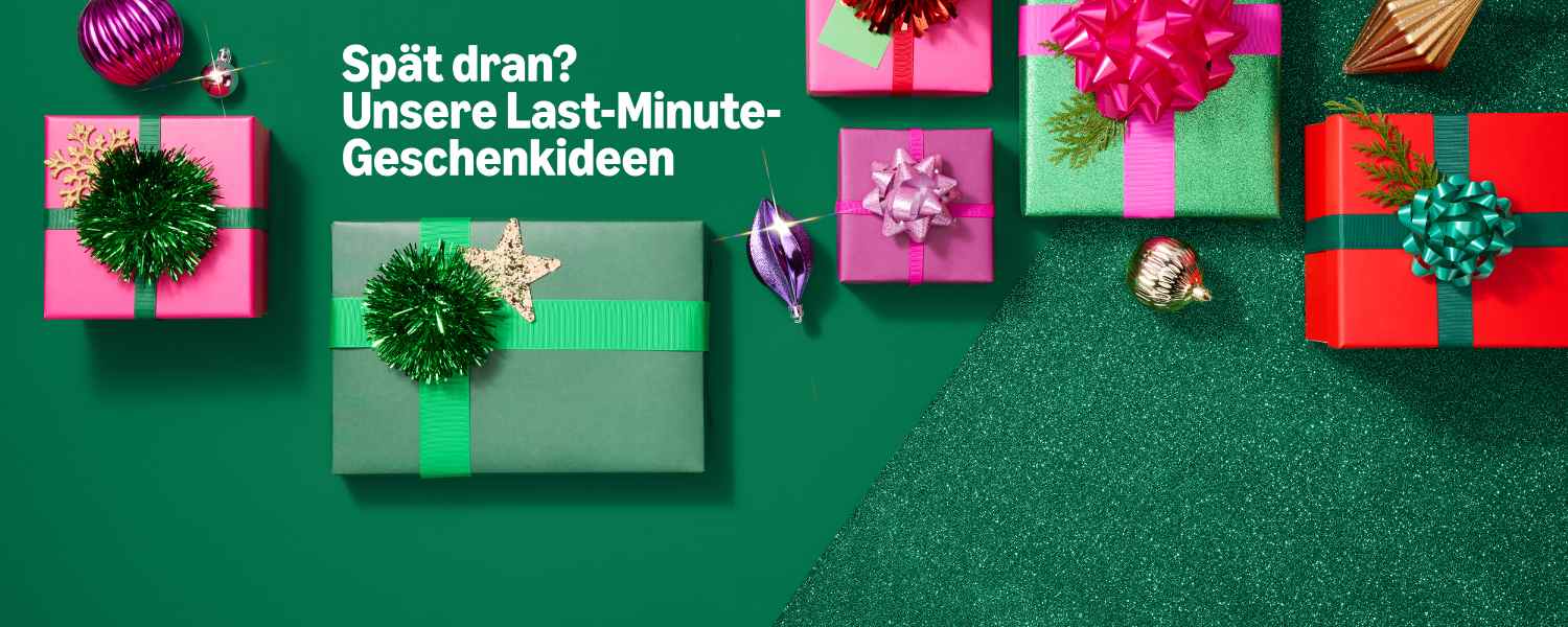 Grüner Hintergrund. Sortiment verpackter Geschenkboxen in verschiedenen Größen und Farben (rosa, rot, grün) mit Schleifen und Ornamenten. Text: "Spät dran? Unsere Last-Minute-Geschenkideen"