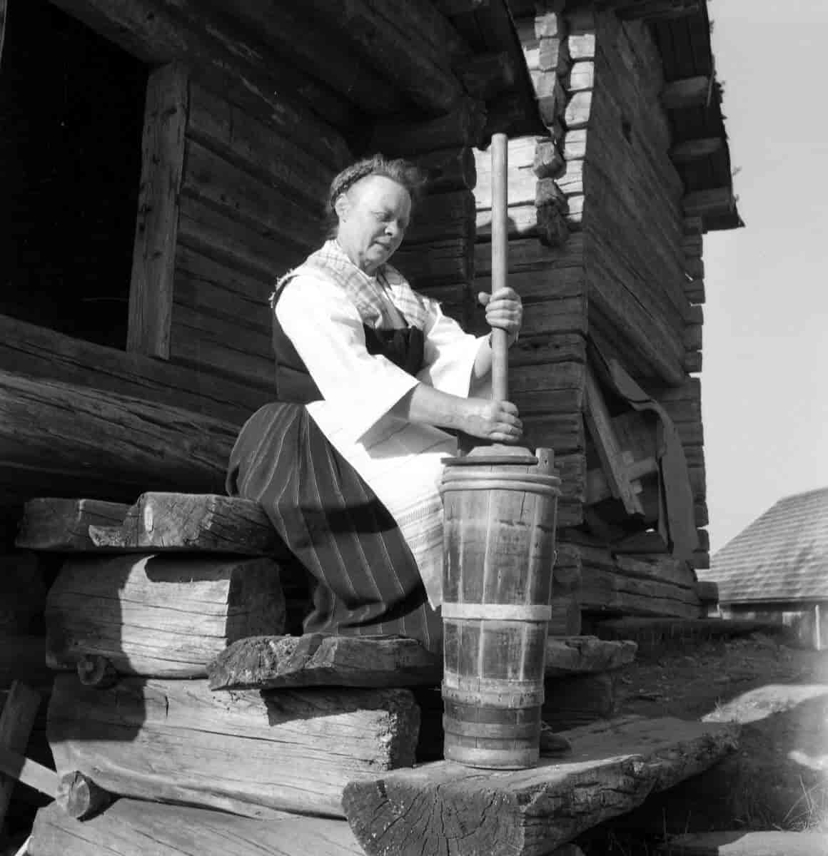 Skogfinsk kvinne kjerner smør på gammel måte på Finnetunet på Grue Finnskog, fotografert rundt 1960-1970