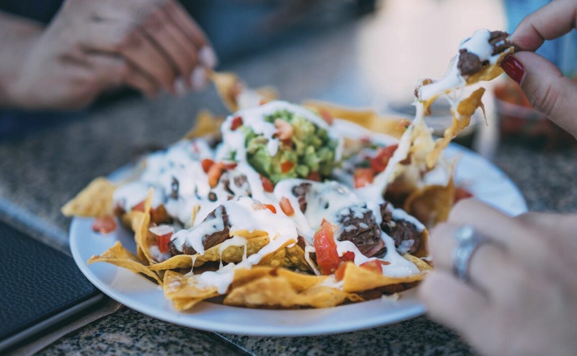 People sharing a plate of nachos.