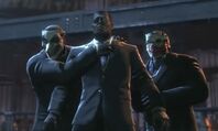 Joker-Black Mask thugs holding warden Joseph hostage.