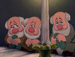 Sneezy, between Bashful and Sleepy, as he grieves for Snow White's "death"