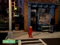 Elmo stands on a street corner in "Hold My Hand"