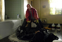 Jesse lifting Emilio's corpse into the bathtub.