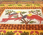 English: Colored sawdust carpet depicting macaws Español: Alfombras de aserrín